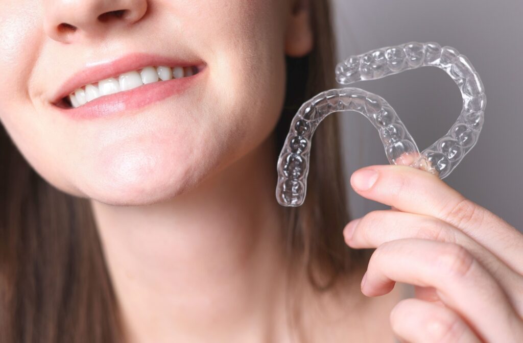 Smiling woman holding two aligners.