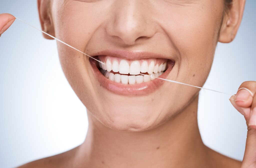 Close-up of a person flossing their teeth to remove plaque and maintain healthy gums, helping prevent gingivitis and gum disease.