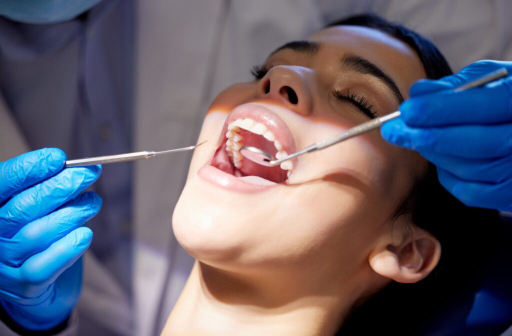 A dental hygienist using tools to provide a dental cleaning for a person with a radiant smile.