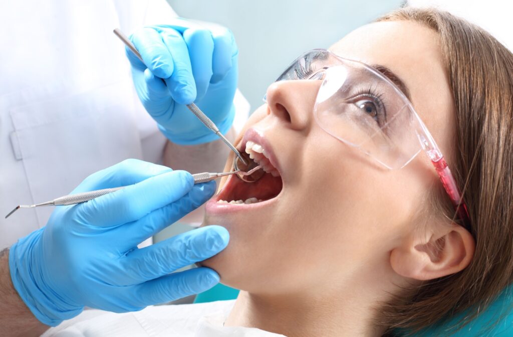 A dentist gently scaling a patient's teeth during their routine dental cleaning and exam.