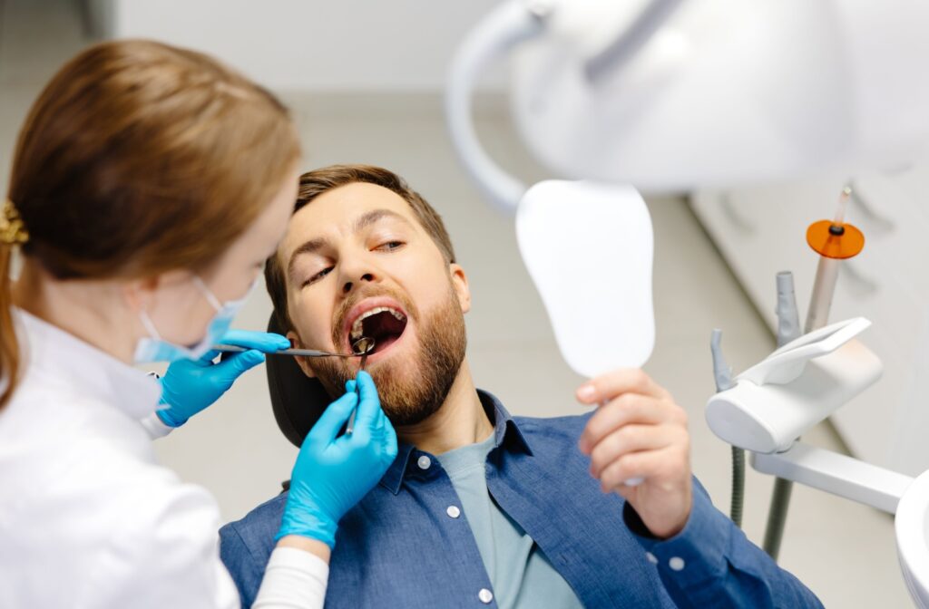 A man having his teeth cleaning by a dentist at the clinic.