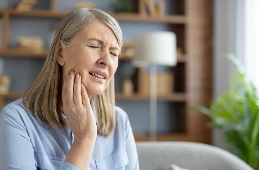 Older woman holding the right side of her jaw in pain.